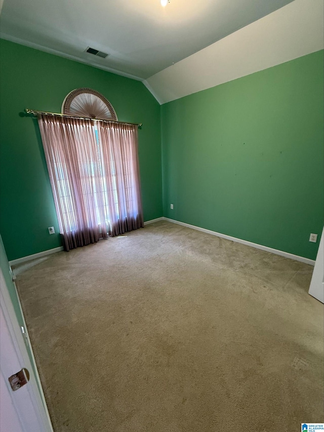 unfurnished room featuring lofted ceiling, carpet flooring, baseboards, and visible vents