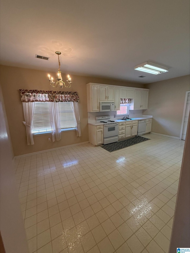 kitchen featuring visible vents, a chandelier, light tile patterned floors, white appliances, and a sink