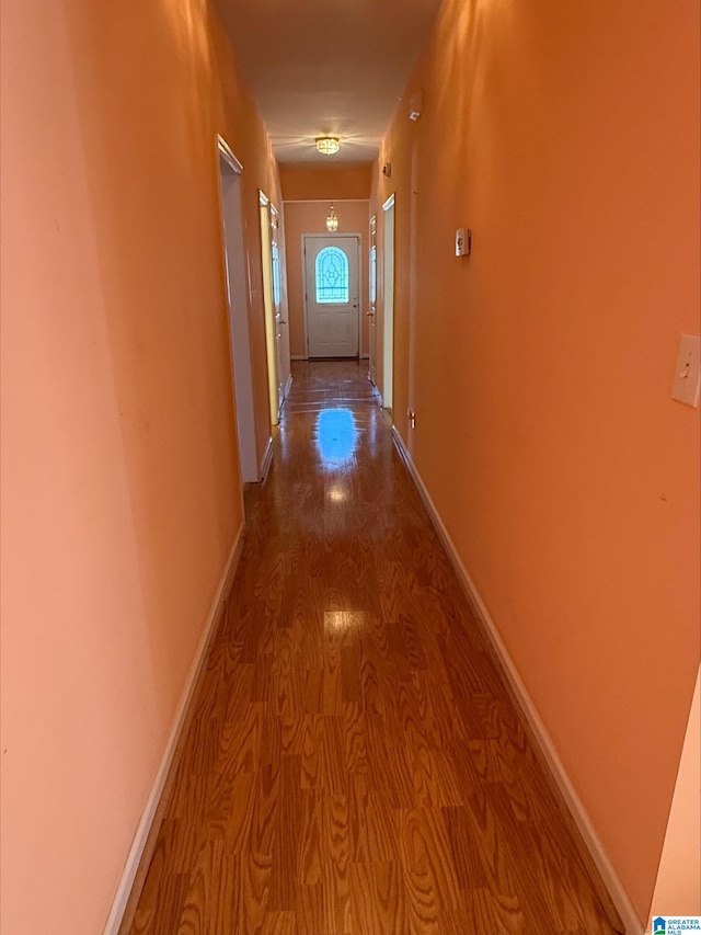 corridor with baseboards and wood finished floors