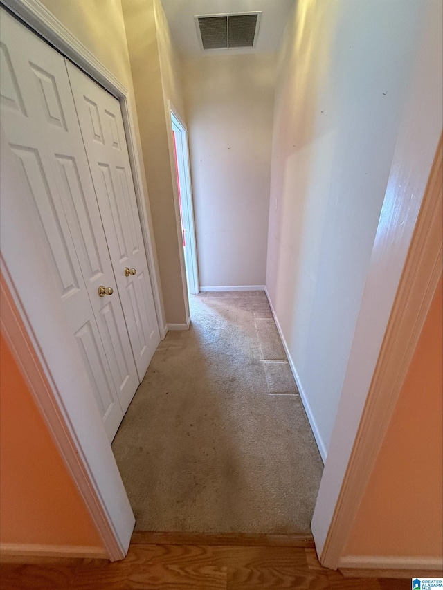 hallway with carpet, visible vents, and baseboards