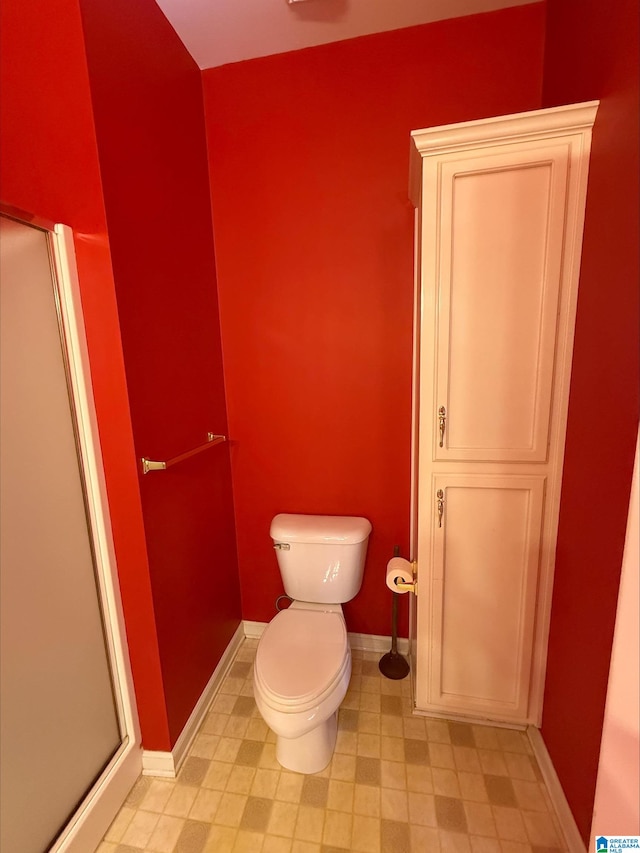 bathroom with an enclosed shower, toilet, and baseboards