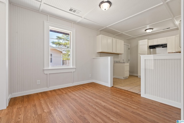 unfurnished living room with light wood-type flooring, visible vents, and baseboards