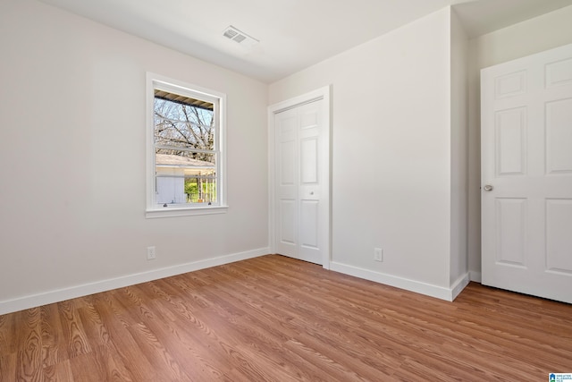 unfurnished bedroom featuring visible vents, baseboards, light wood-type flooring, and a closet