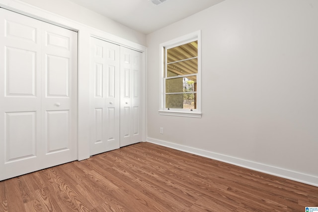 unfurnished bedroom featuring visible vents, baseboards, and wood finished floors