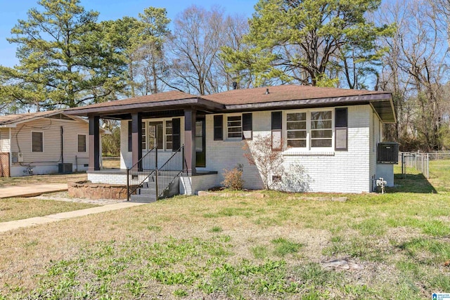 view of front of house featuring brick siding, a front lawn, fence, covered porch, and crawl space