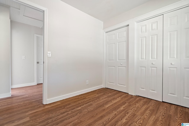 unfurnished bedroom featuring wood finished floors, baseboards, and a closet