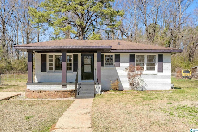 bungalow with a front yard, fence, covered porch, and brick siding