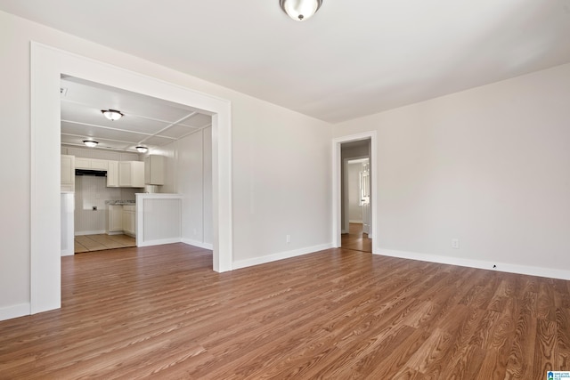 unfurnished living room with baseboards and light wood-type flooring