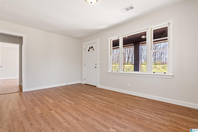 empty room featuring visible vents, light wood-style flooring, and baseboards