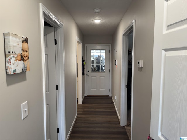 hall with baseboards, a textured ceiling, and dark wood-style flooring