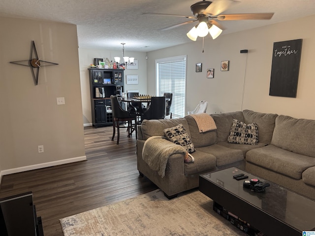 living room with baseboards, a textured ceiling, wood finished floors, and ceiling fan with notable chandelier