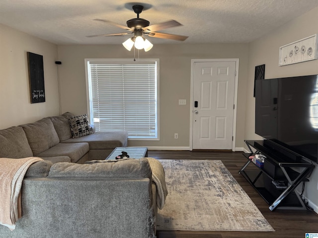 living area with ceiling fan, baseboards, dark wood-style flooring, and a textured ceiling