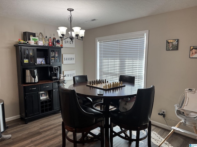 dining area featuring visible vents, baseboards, a notable chandelier, and wood finished floors