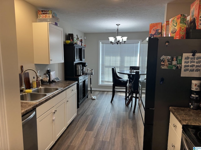 kitchen with dark wood-type flooring, a sink, dark countertops, a textured ceiling, and appliances with stainless steel finishes