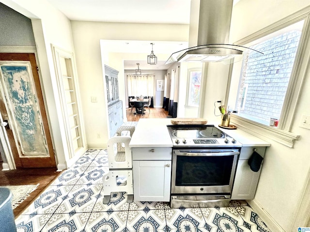 kitchen with light countertops, electric stove, island exhaust hood, and a wealth of natural light