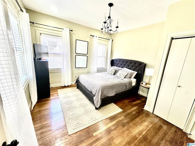 bedroom with baseboards, an inviting chandelier, and wood finished floors