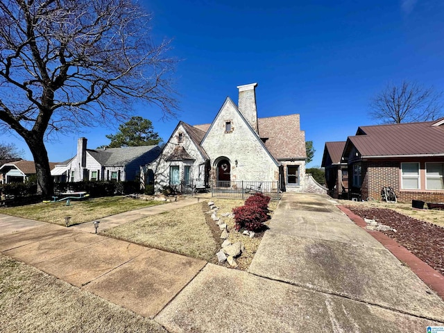 view of front facade featuring brick siding, a front lawn, and a chimney