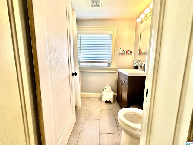 bathroom featuring visible vents, toilet, vanity, and baseboards