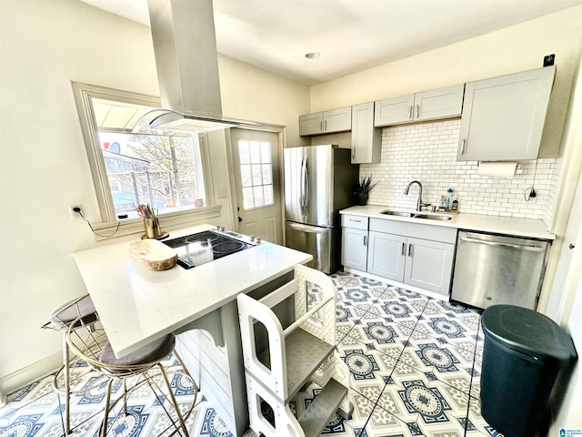 kitchen featuring backsplash, light countertops, island range hood, stainless steel appliances, and a sink