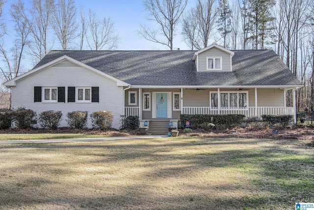 view of front of home with a front lawn, brick siding, covered porch, and a shingled roof