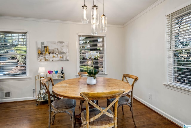 dining room featuring visible vents, ornamental molding, baseboards, and wood finished floors