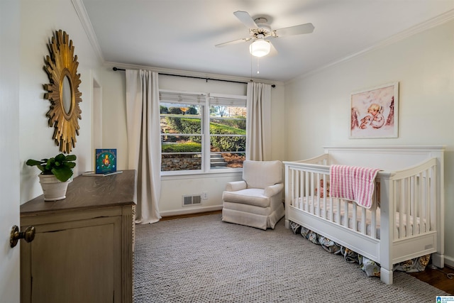 bedroom with a crib, crown molding, baseboards, and a ceiling fan