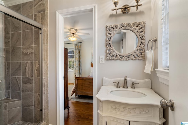 full bath with connected bathroom, a stall shower, vanity, and wood finished floors