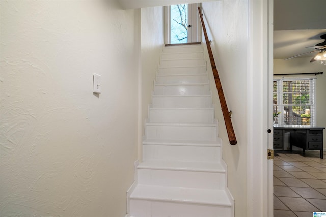 staircase with tile patterned floors, a healthy amount of sunlight, a ceiling fan, and a textured wall