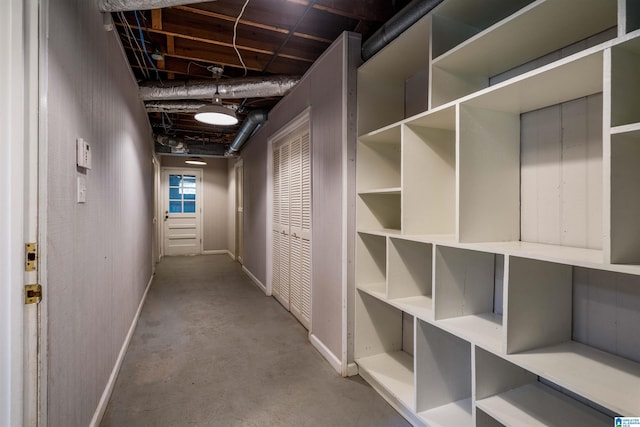 corridor featuring concrete flooring and baseboards