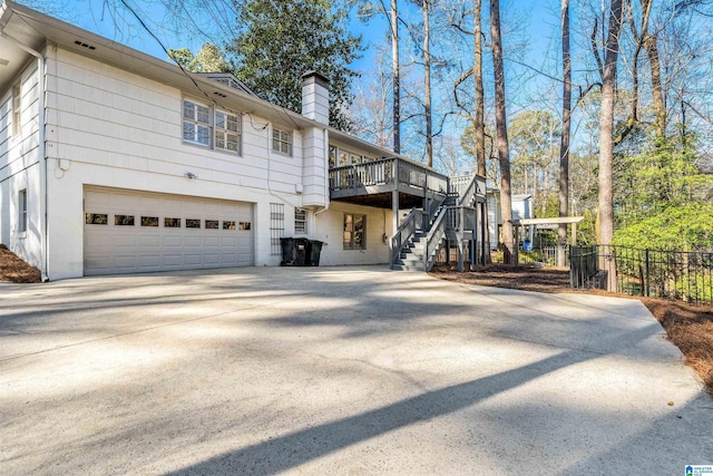 rear view of property with fence, driveway, a chimney, stairs, and a garage