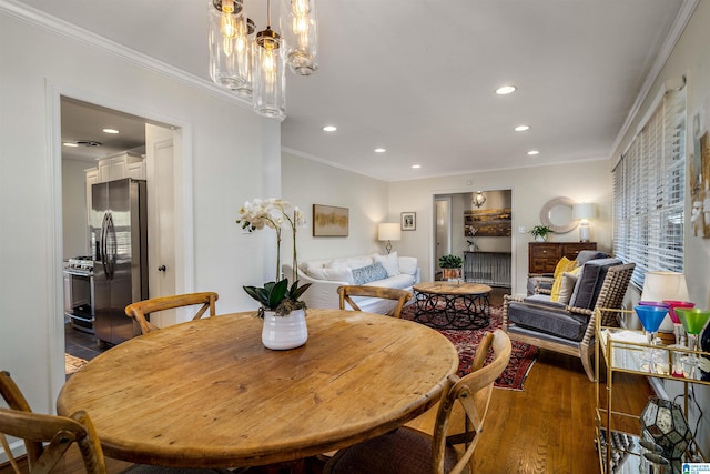 dining space featuring recessed lighting, a chandelier, wood finished floors, and crown molding