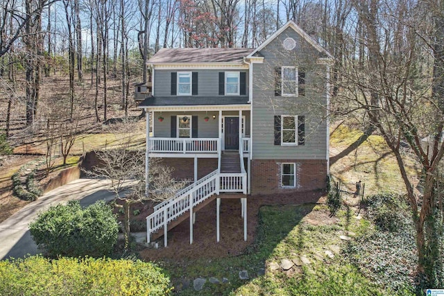 view of front of property featuring stairway, brick siding, a porch, and driveway