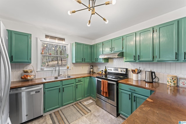 kitchen featuring a sink, stainless steel appliances, under cabinet range hood, tasteful backsplash, and a chandelier