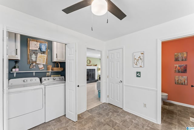 laundry area with independent washer and dryer, a ceiling fan, cabinet space, a fireplace, and baseboards