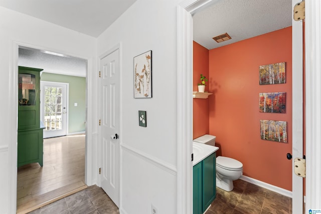 bathroom with visible vents, baseboards, toilet, and a textured ceiling