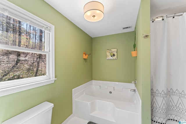 bathroom featuring a bath, visible vents, a healthy amount of sunlight, and toilet