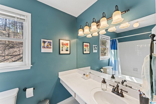 bathroom with curtained shower, toilet, and a sink