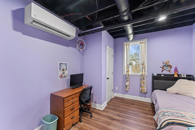 bedroom featuring a wall mounted air conditioner, baseboards, and wood finished floors