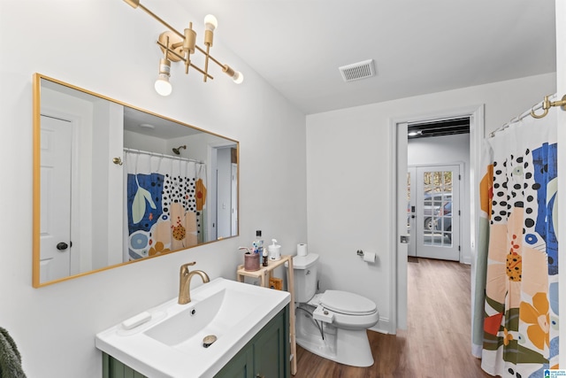 bathroom featuring visible vents, toilet, curtained shower, wood finished floors, and vanity