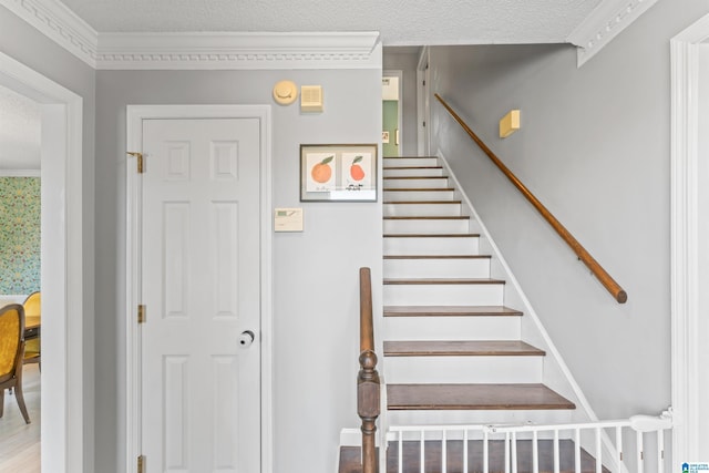 stairs featuring crown molding and a textured ceiling