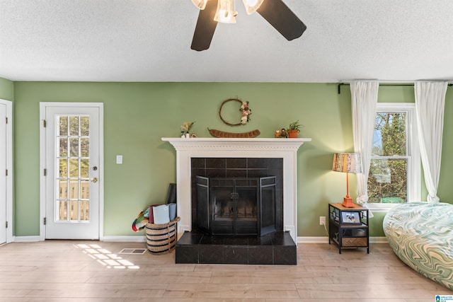 living room featuring visible vents, baseboards, a fireplace, wood finished floors, and a textured ceiling