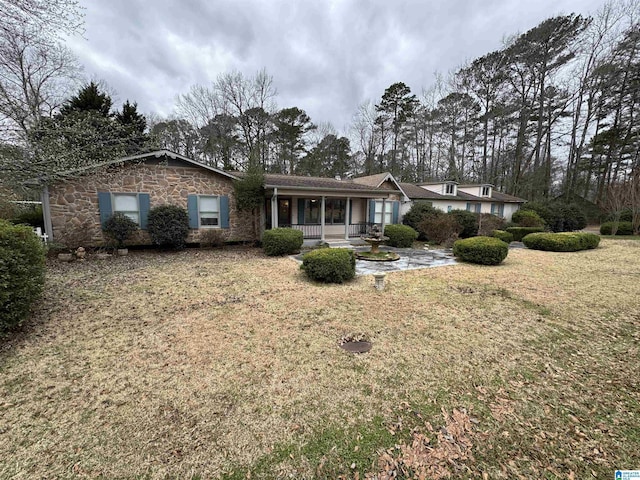 view of front of home with stone siding, covered porch, and a front yard