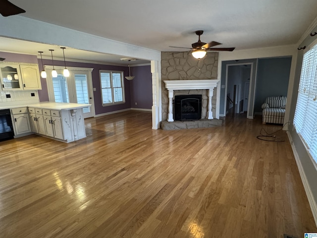 unfurnished living room featuring baseboards, ceiling fan, ornamental molding, a fireplace, and wood finished floors