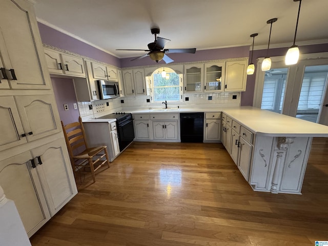 kitchen featuring crown molding, a peninsula, light wood-style floors, black appliances, and a sink