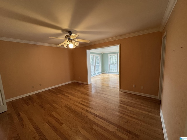 empty room featuring ornamental molding, baseboards, and wood finished floors