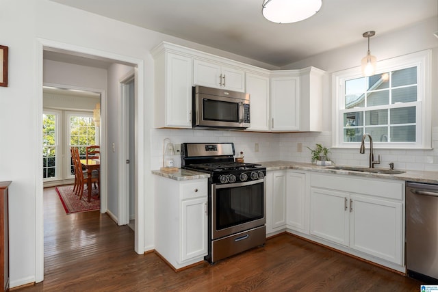 kitchen with a sink, stainless steel appliances, tasteful backsplash, and dark wood finished floors