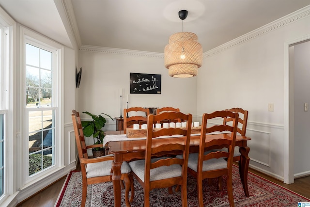 dining area featuring wood finished floors, a healthy amount of sunlight, and ornamental molding