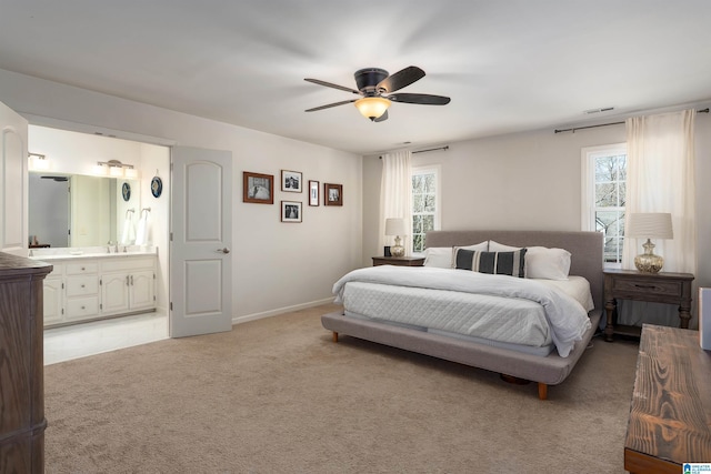 bedroom with a ceiling fan, visible vents, baseboards, ensuite bathroom, and light carpet