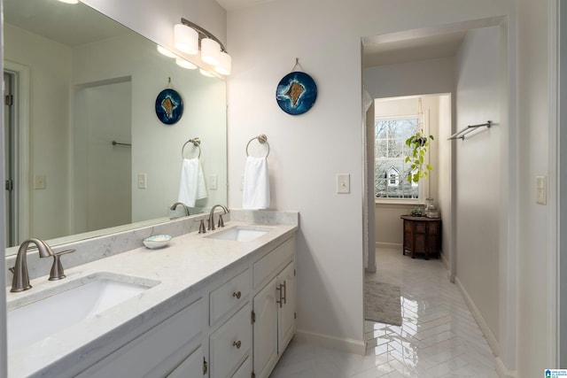 full bathroom with double vanity, baseboards, and a sink