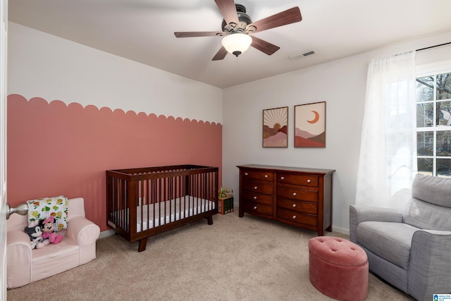 bedroom with visible vents, carpet flooring, a crib, and ceiling fan